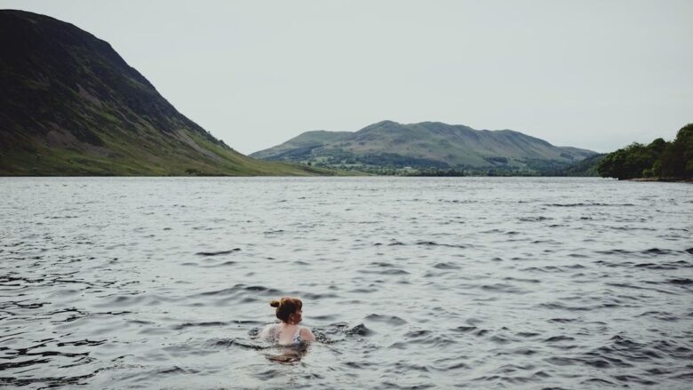 Nageuse en eau libre dans un lac entouré de montagnes verdoyantes