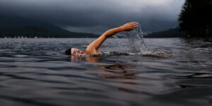 Nageur avançant dans un lac sombre sous un ciel orageux